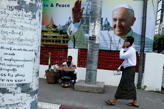 A man walks past a banner welcoming Pope Francis, ahead of his visit to Burma