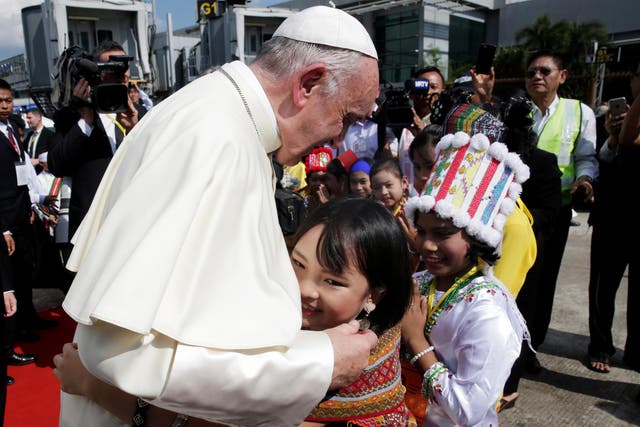 A girl embraces Pope Francis as he arrives at Yangon International Airport