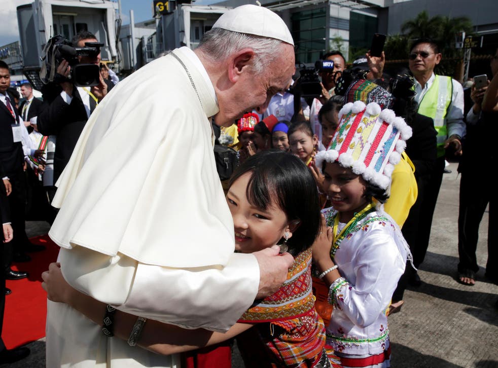 A girl embraces Pope Francis as he arrives at Yangon International Airport