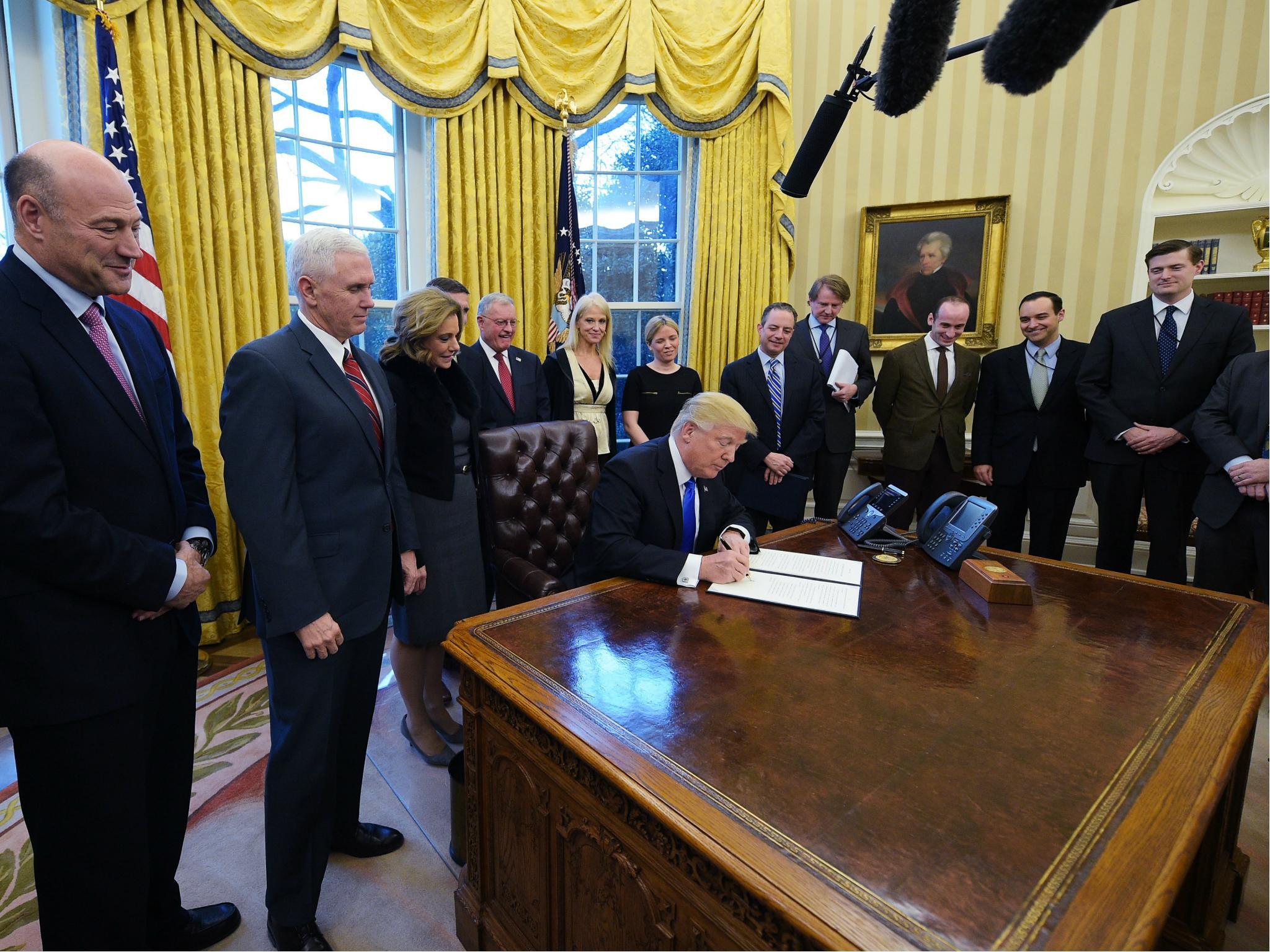 US President Donald Trump signs an executive order on ethics commitments by the executive branch appointees in the Oval Office on 28 January 2017