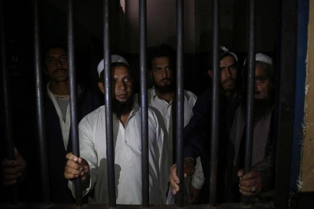 Relatives of a newlywed couple stand behind bars at a police station in Karachi, Pakistan