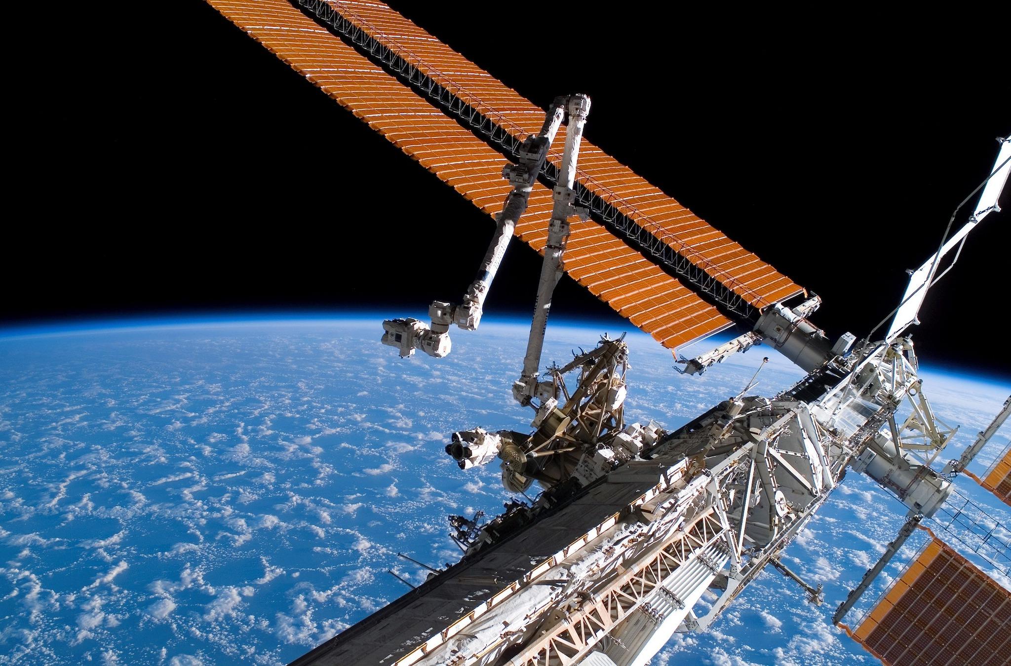 The Canadarm2 (center) and solar array panel wings on the International Space Station are extended during the mission's first planned session of extravehicular activity while Space Shuttle Endeavour (STS-118) was docked with the International Space Station