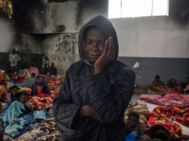 A migrant holds his head as he stands in a packed room at the Tariq Al-Matar detention centre on the outskirts of the Libyan capital Tripoli on November 27, 2017.