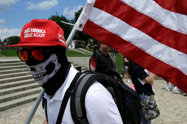 A masked demonstrator in a 'Make America Great Again' cap carries a US flag as self proclaimed 'White Nationalists', white supremacists and 'Alt-Right' activists gathered in Washington in June this year