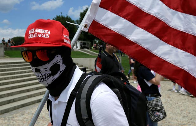 A masked demonstrator in a 'Make America Great Again' cap carries a US flag as self proclaimed 'White Nationalists', white supremacists and 'Alt-Right' activists gathered in Washington in June this year