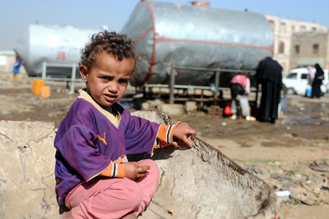  A Yemeni child sits on a wheelbarrow as he waits for his mother to fill their jerry cans with clean water