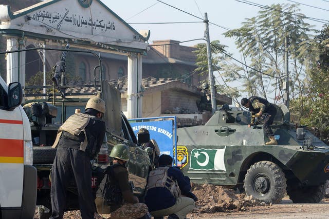 Pakistani security personnel take position outside an Agriculture Training Institute after an attack by Taliban militants in Peshawar