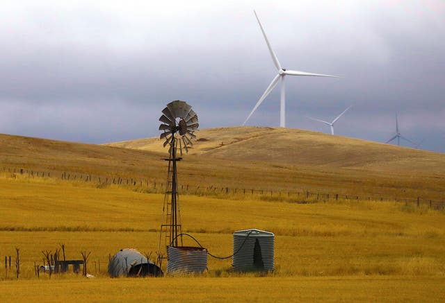 An old windmill stands in front of wind turbines in a paddock near the Hornsdale Power Reserve, featuring the world's largest lithium ion battery made by Tesla, located on the outskirts of the South Australian town of Jamestown, in Australia