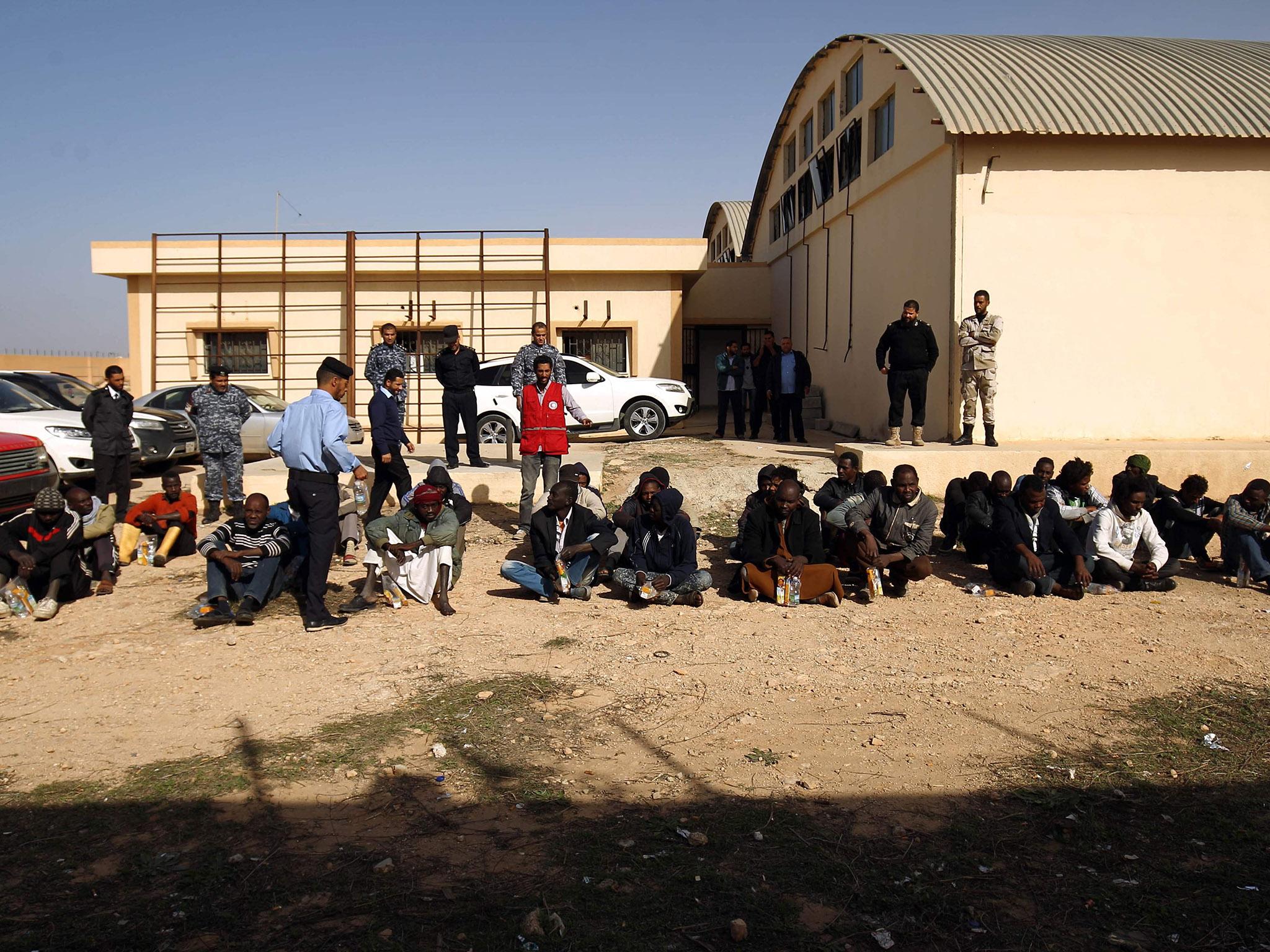 Sub-Saharan migrants sit at the Qanfouda detention centre, in the southern outskitrs of Benghazi