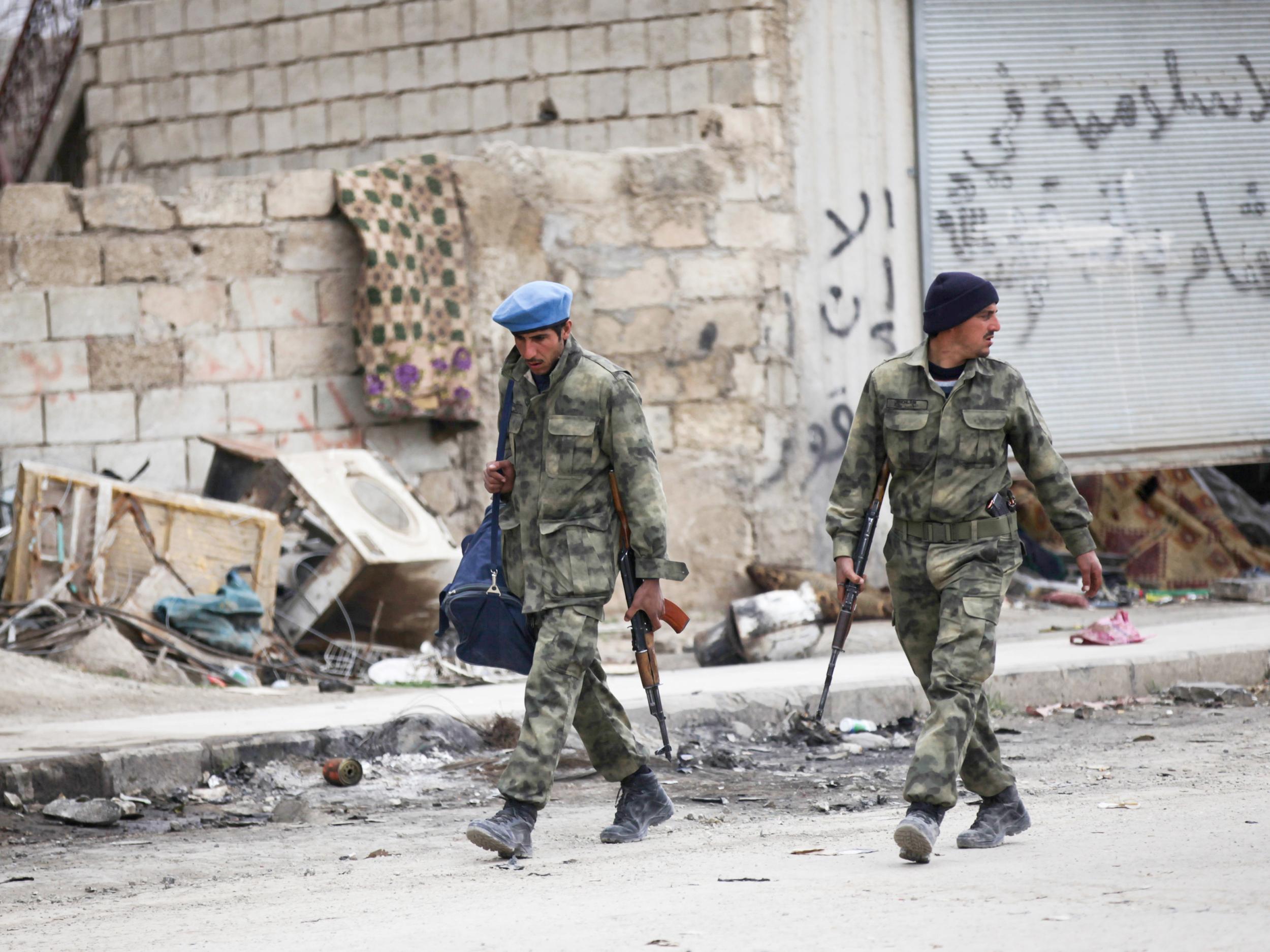 Members of the Free Police walk along a street in al-Rai, Syria