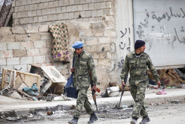 Members of the Free Police walk along a street in al-Rai, Syria