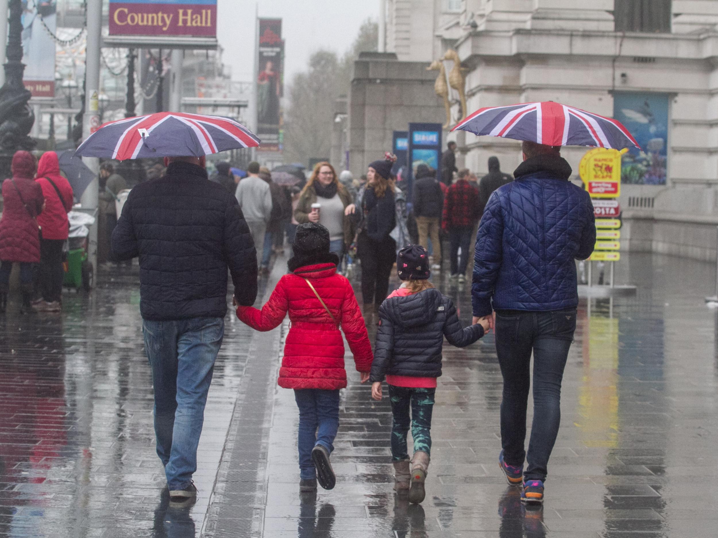 Pedestrians shelter from the rain on Westminster Bridge