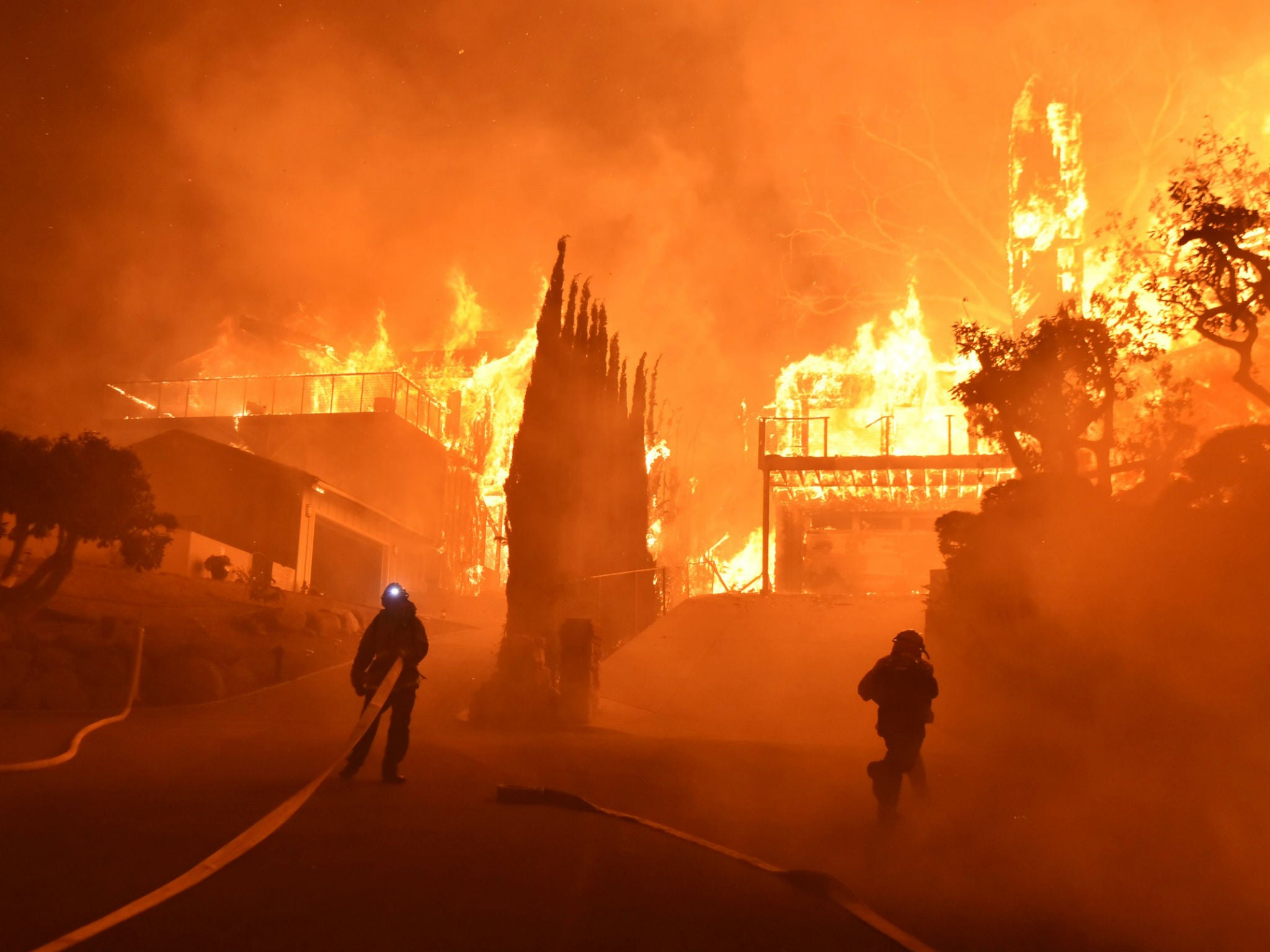 Firefighters work to put out a blaze burning homes in Ventura, California