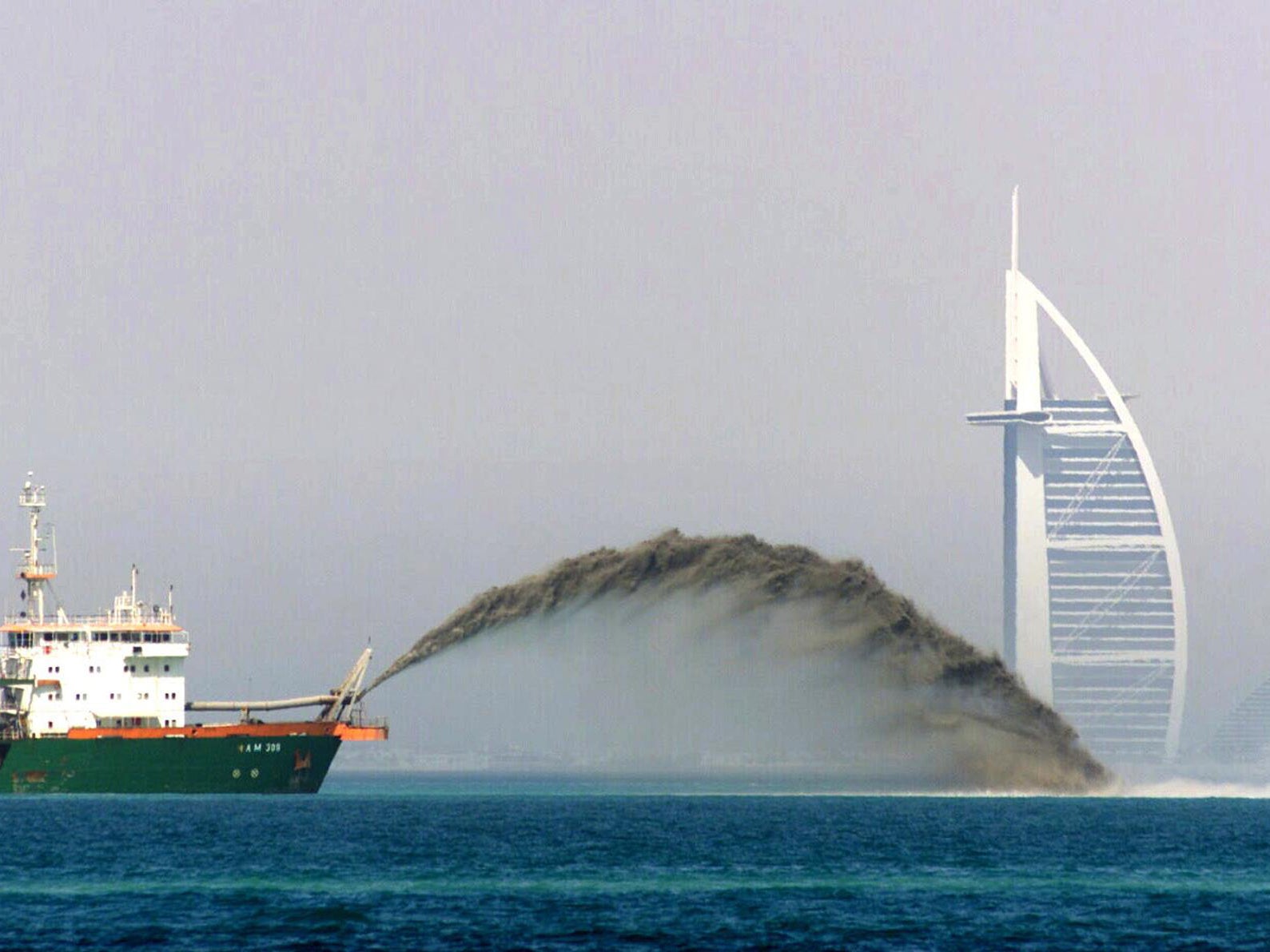 A dredger boat dumps huge amounts of sand into the sea to create new land for building development (AFP/Getty)