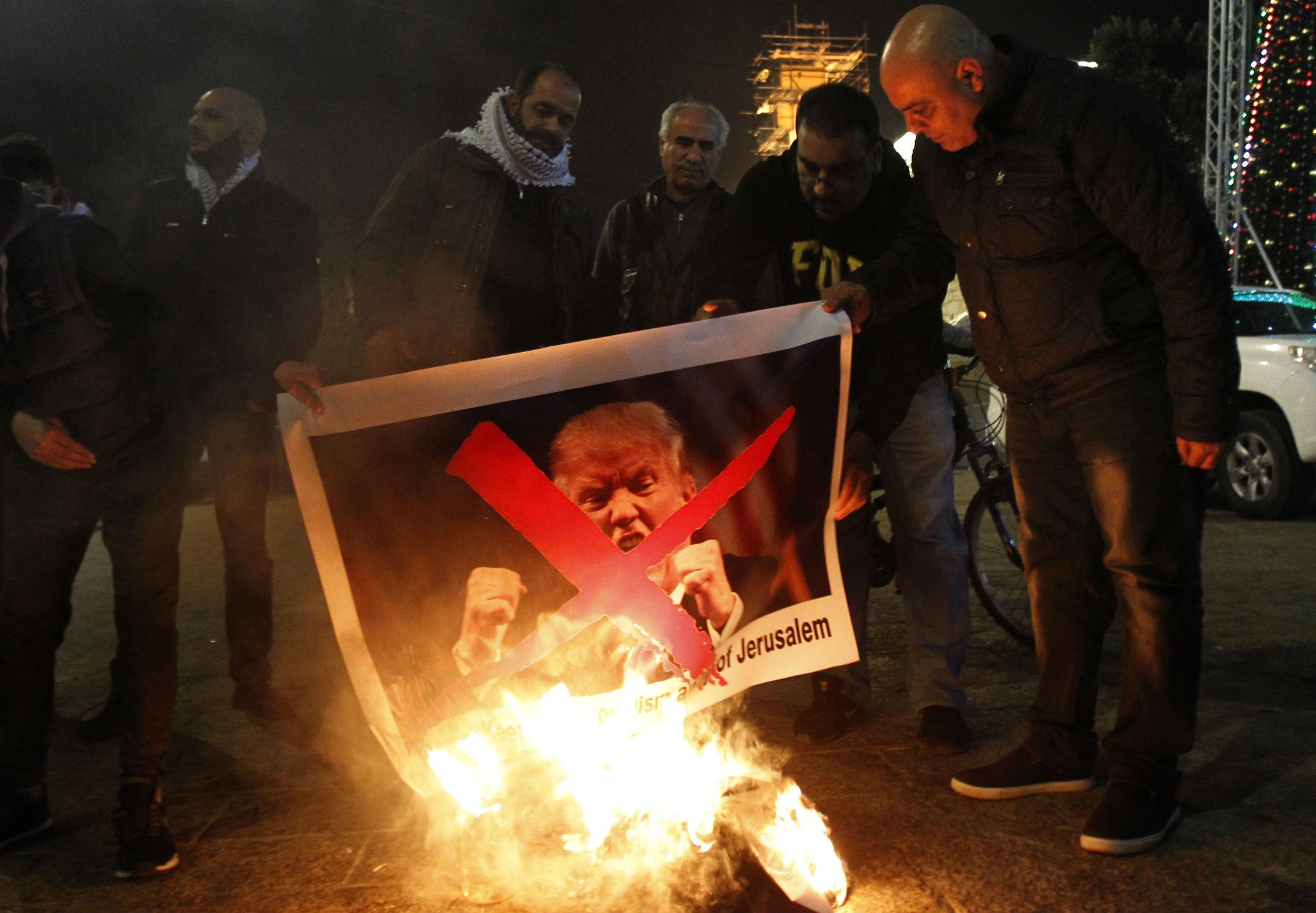 Palestinian protesters burn pictures of US President Donald Trump at the manger square in Bethlehem on December 5, 2017 (MUSA AL SHAER/AFP/Getty Images)