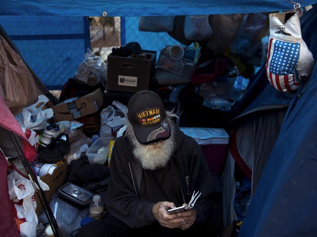 Theodore Neubauer, a 78-year-old Vietnam War veteran, who is homeless, looks at his smartphone while passing time in his tent in Los Angeles