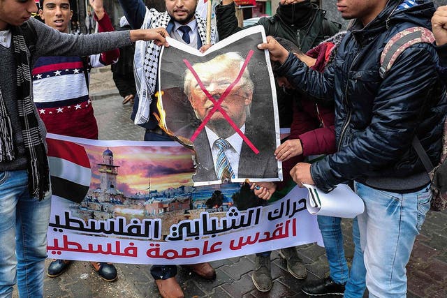 Palestinian protesters prepare to burn a picture of Donald Trump in the southern Gaza Strip town of Rafah