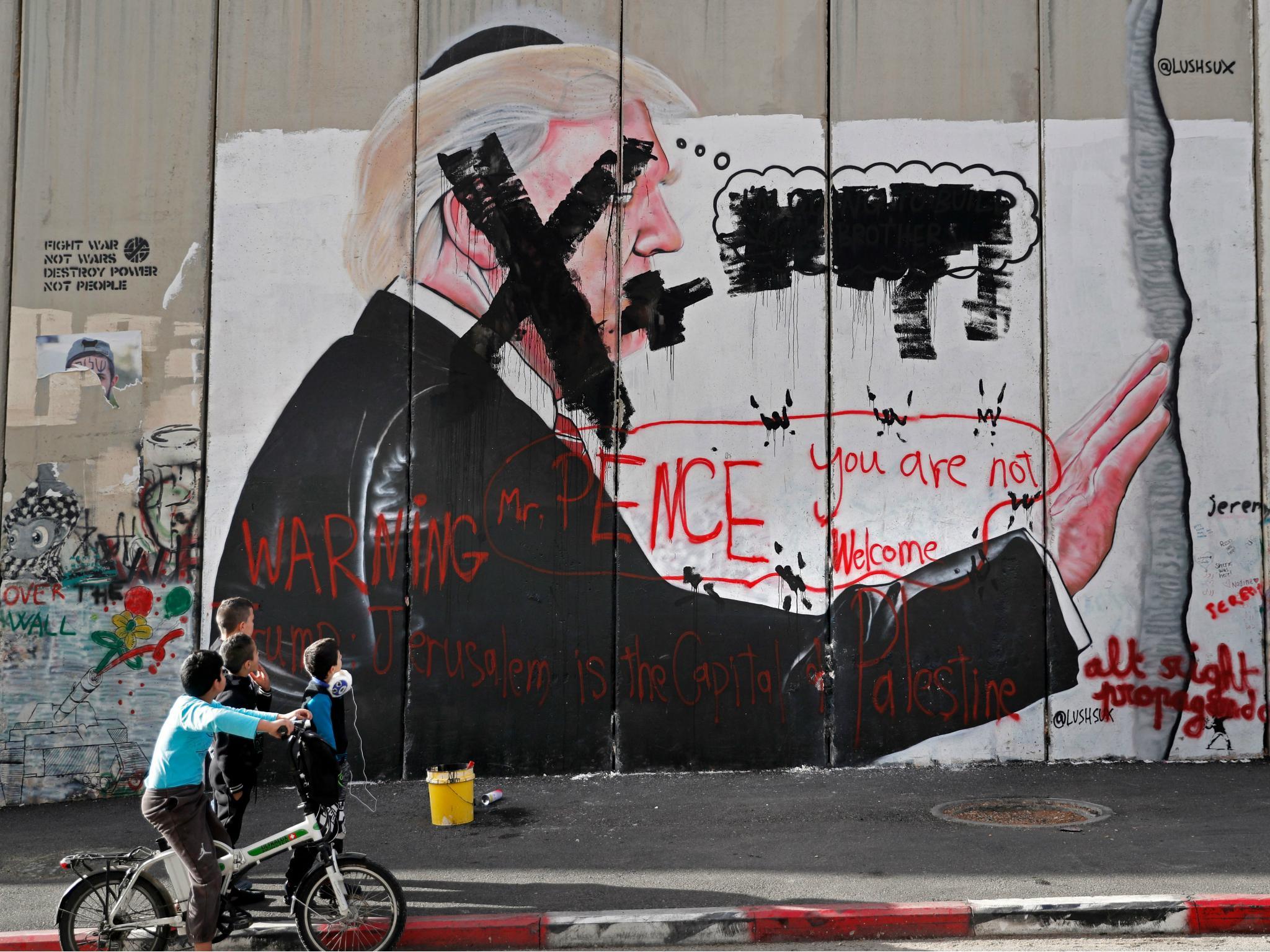 Palestinian children look at vandalised graffiti depicting US President Donald Trump and slogans against US Vice President Mike Pence painted on Israel's controversial separation barrier in the West Bank city of Bethlehem.