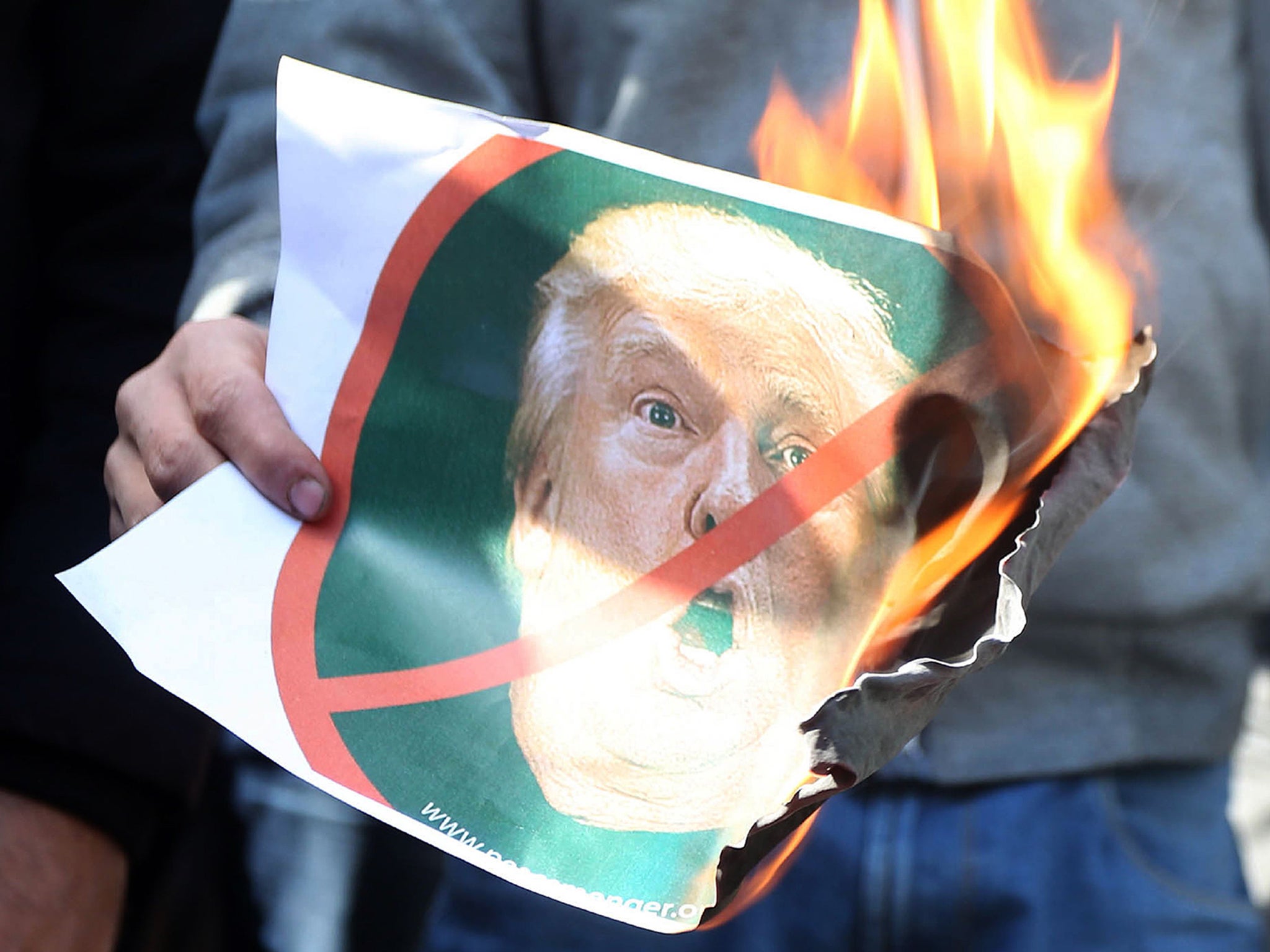 A Palestinian protester burns an image of Donald Trump