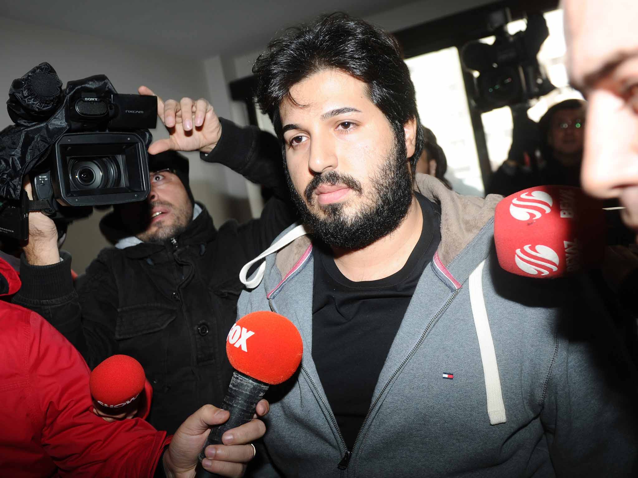 Detained Azerbaijani businessman Reza Zarrab (C) is surrounded by journalists as he arrives at a police center in Istanbul on December 17 ,2013