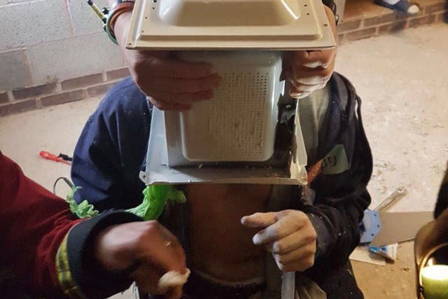 Jimmy Swingler with his head stuck in a microwave as firefighters attempt to remove it 