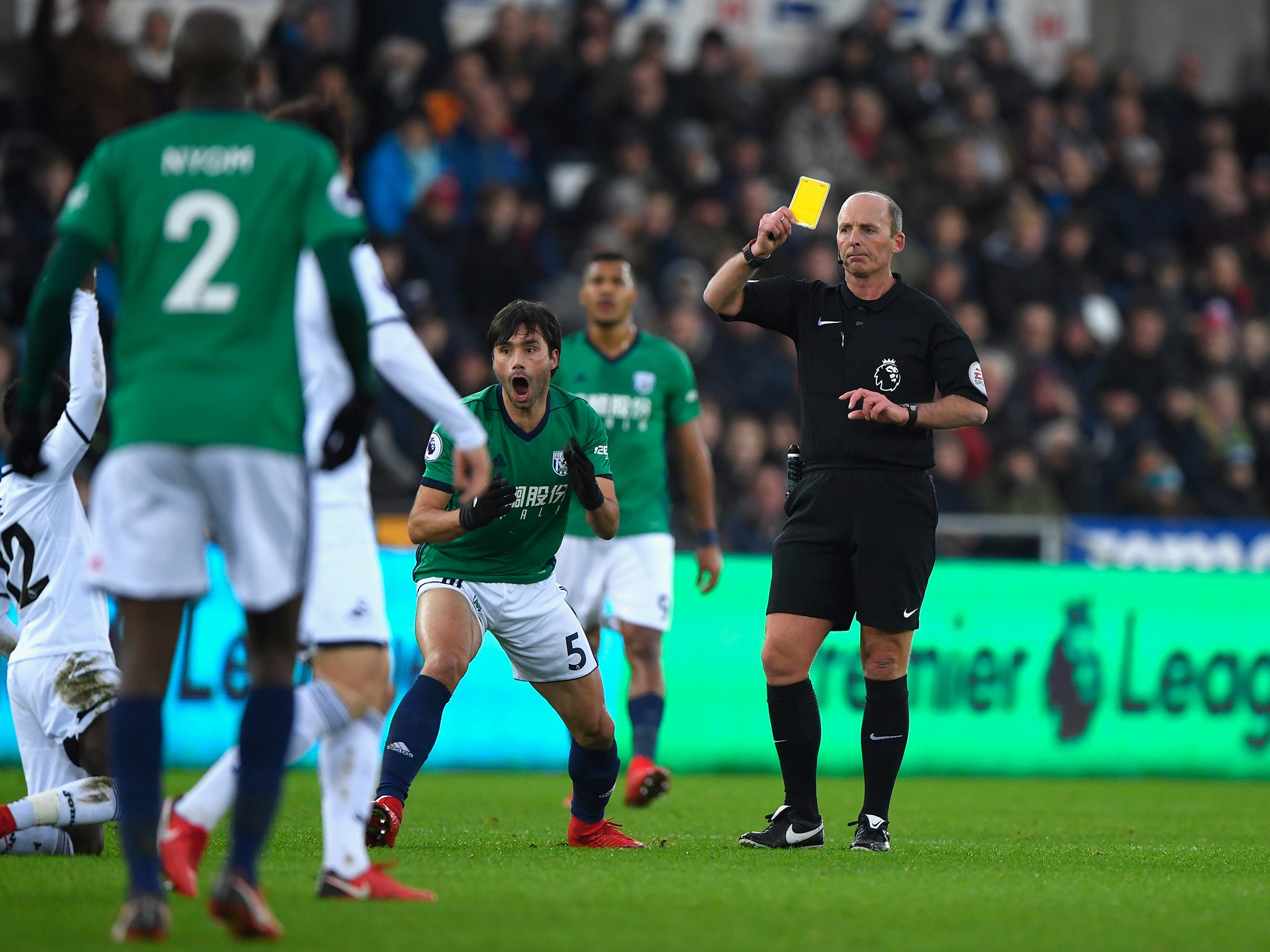 Referee Mike Dean books Claudio Yacob for a foul