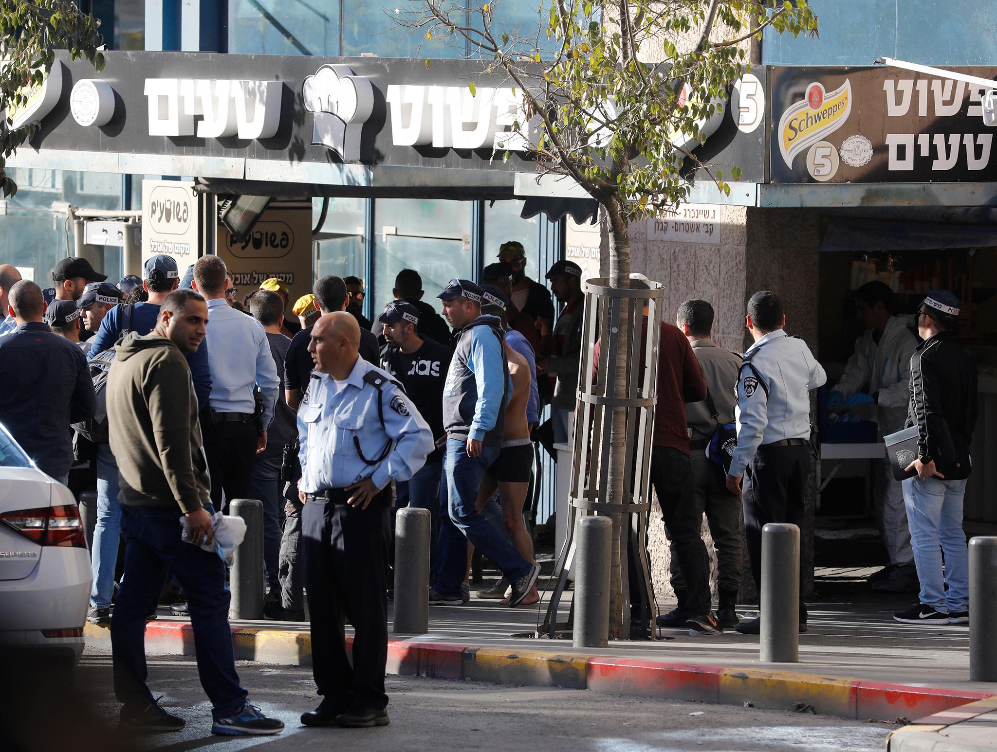 Police gather at the scene where an Israeli security guard was stabbed at a Jerusalem bus station