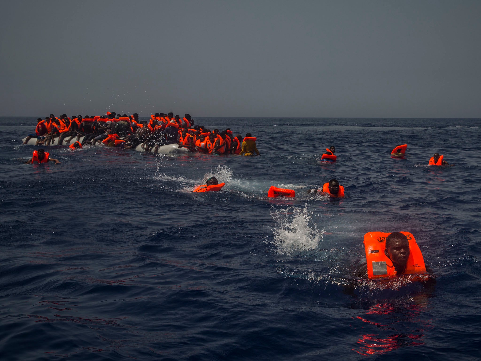 Miigrants try to reach a rescue boat from the Spanish aid organisation Proactive Open Arms after falling from a punctured rubber boat in the Mediterranean about 12 miles north of Sabratha, Libya