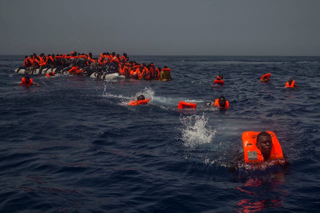 African migrants try to reach a rescue boat from the Spanish aid organisation Proactive Open Arms after falling from a punctured rubber boat in the Mediterranean about 12 miles north of Sabratha, Libya