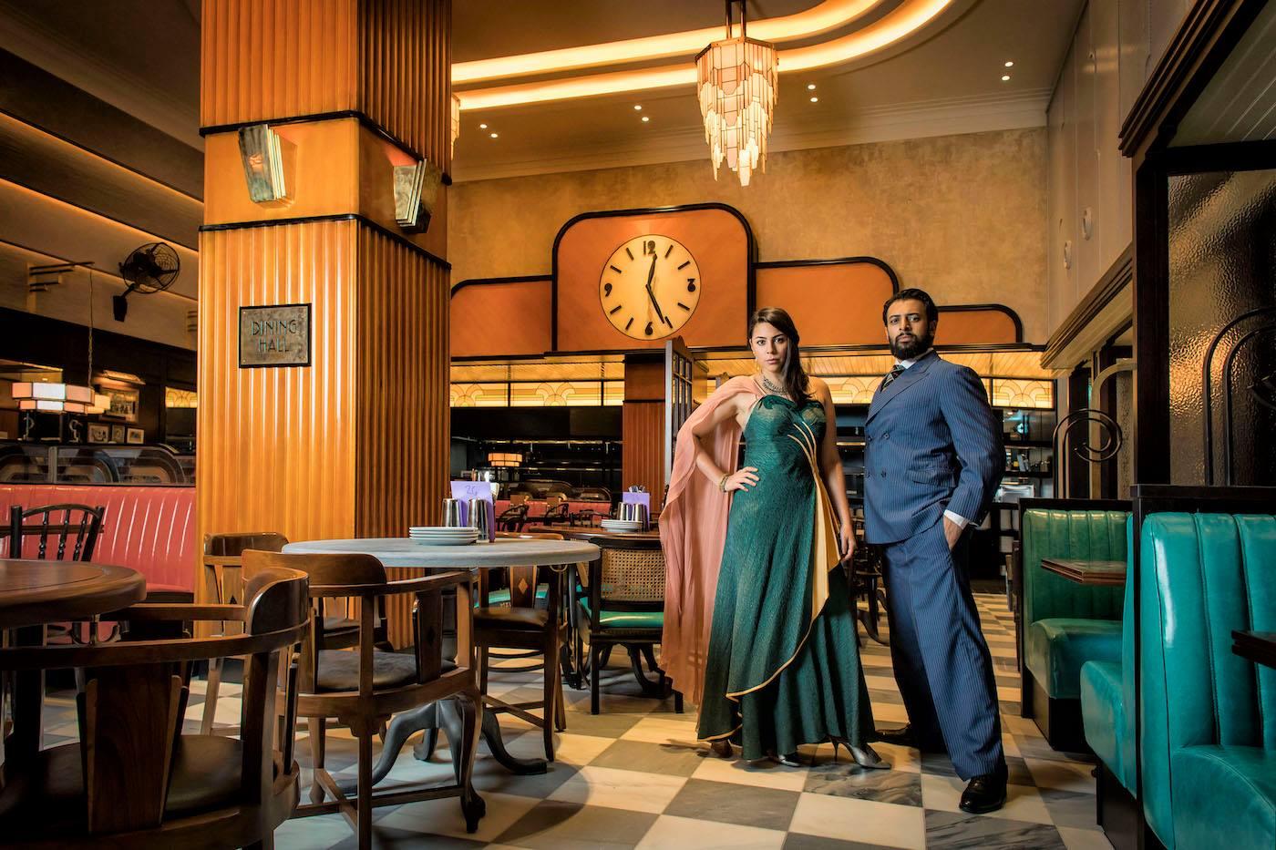 Actors Vikash Bhai as Cyrus and Sophie Khan Levy as Ursula striking a pose in the Bombay Roxy.