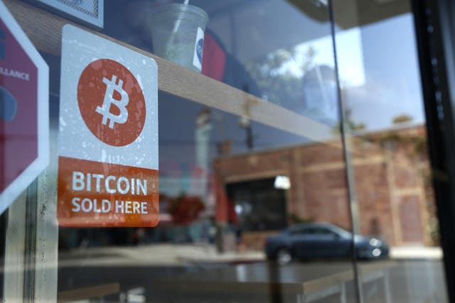 A bitcoin sticker is seen in the window of Locali Conscious Convenience store, where one of Southern California's first two bitcoin-to-cash ATMs began operating