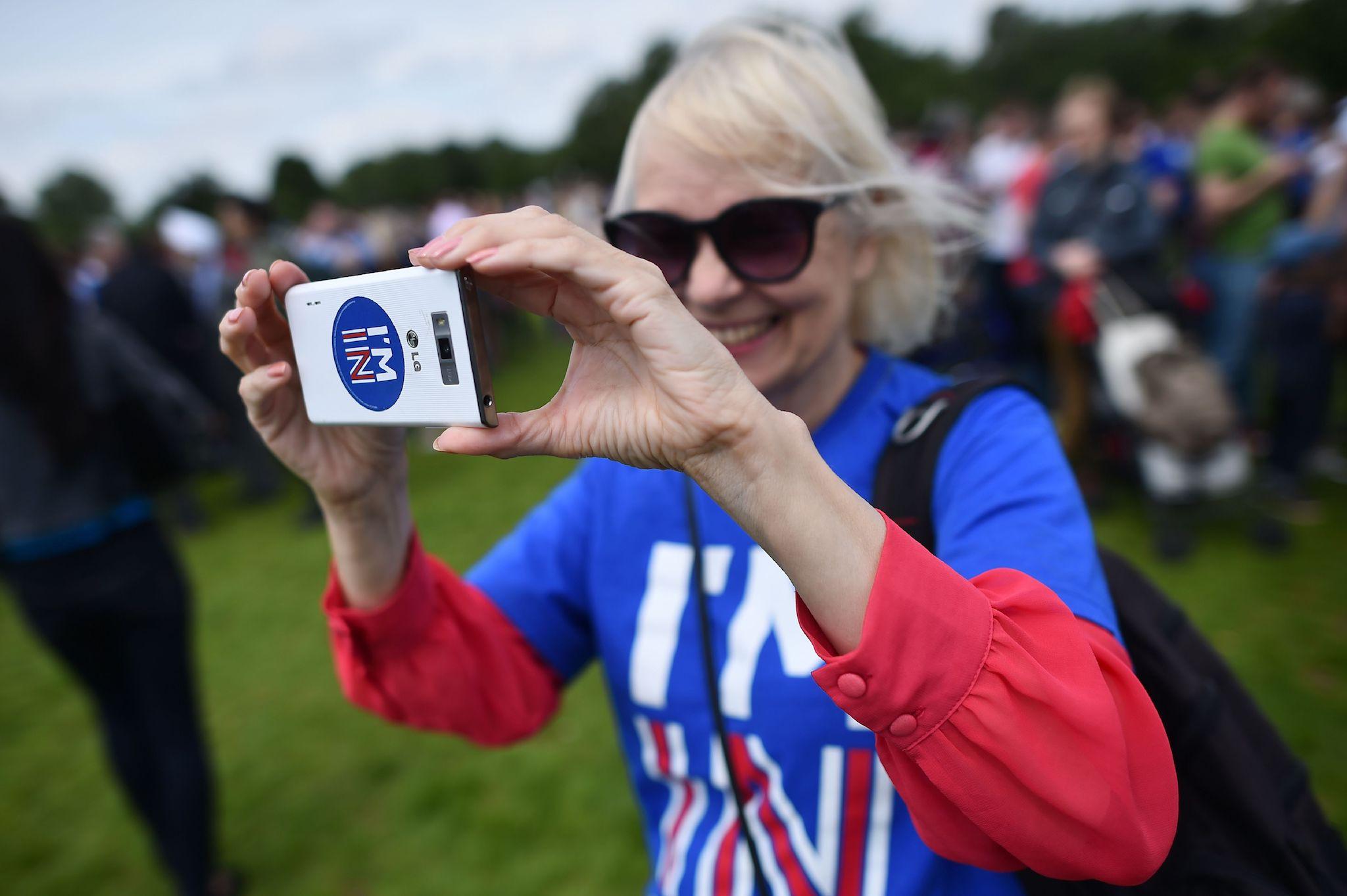 A woman uses a smartphone to take a photograph as she attends a rally for 'Britain Stronger in Europe', the official 'Remain' campaign group seeking to a avoid Brexit