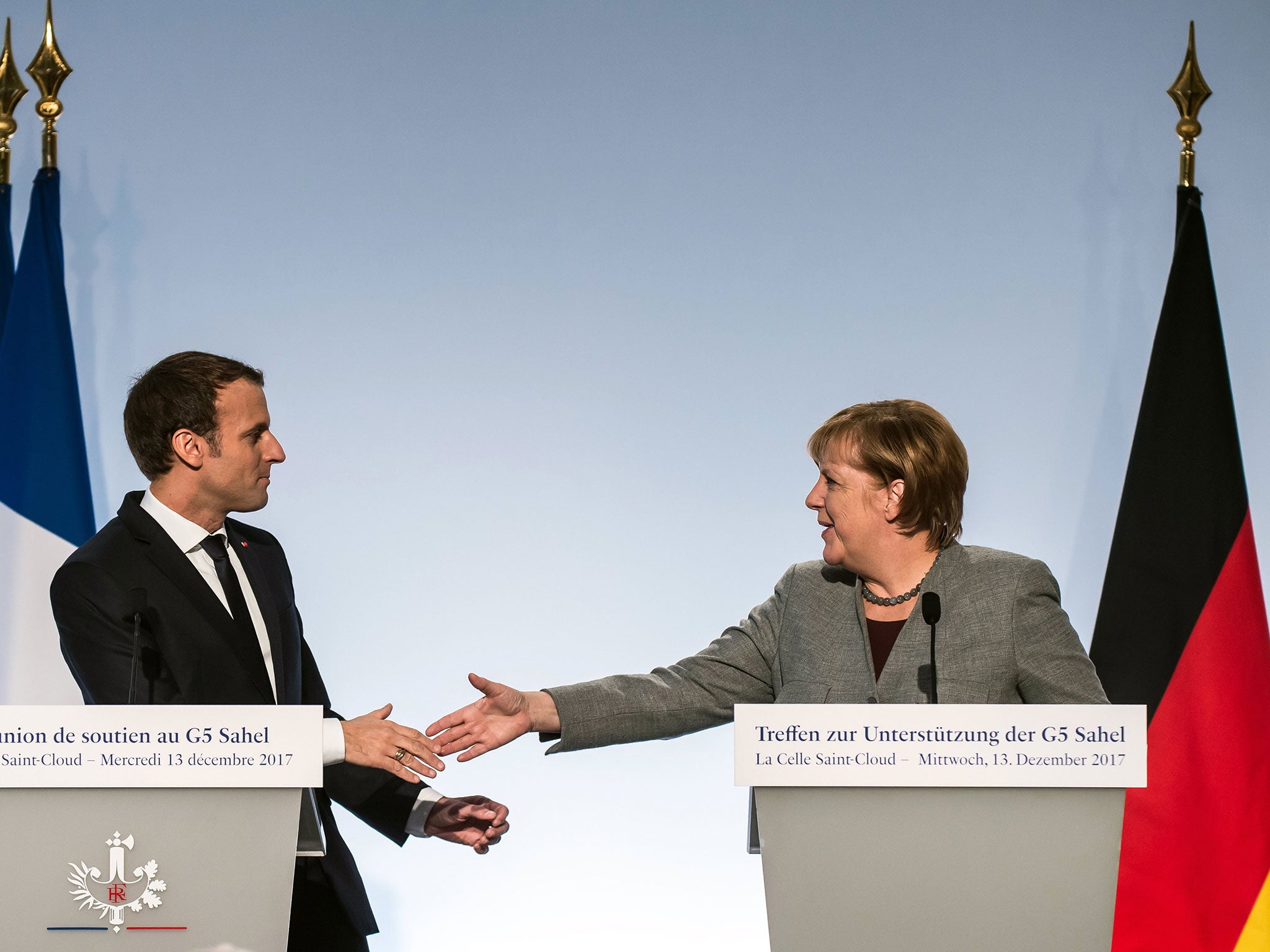 President Emmanuel Macron (L) and German Chancellor Angela Merkel (R) shake hands during a media conference