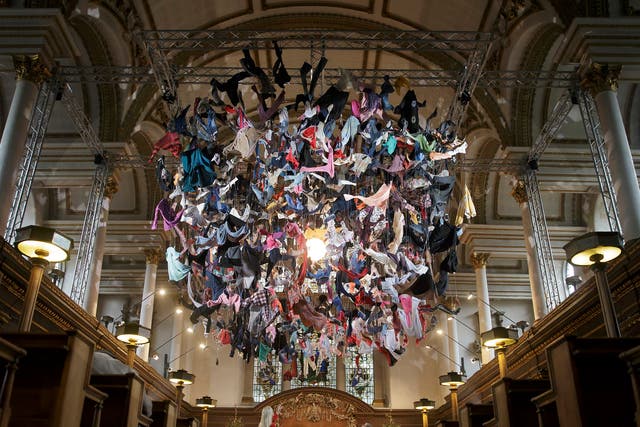 People view an installation artwork called Suspended, composed of items of clothing discarded by refugees on their arrival at Lesvos, by artist Arabella Dorman, at St James's Church on Piccadilly in London