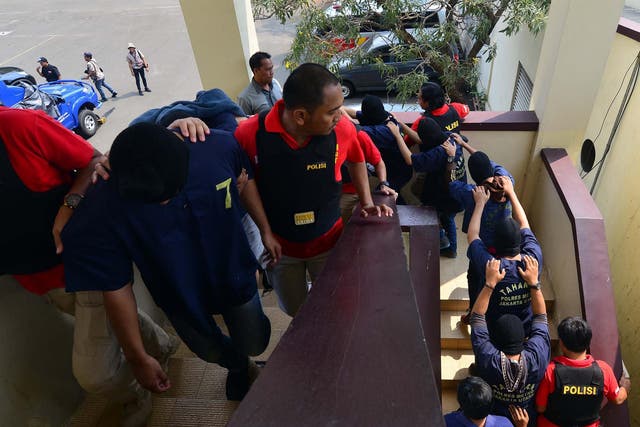 Police escort the detained men during a press conference in the Indonesian capital