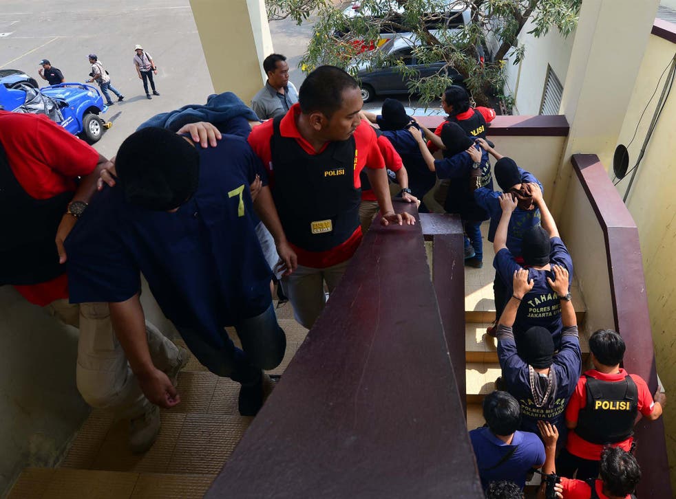 Police escort the detained men during a press conference in the Indonesian capital