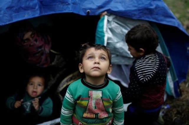 A Syrian refugee boy outside his family tent in a makeshift camp (Reuters)