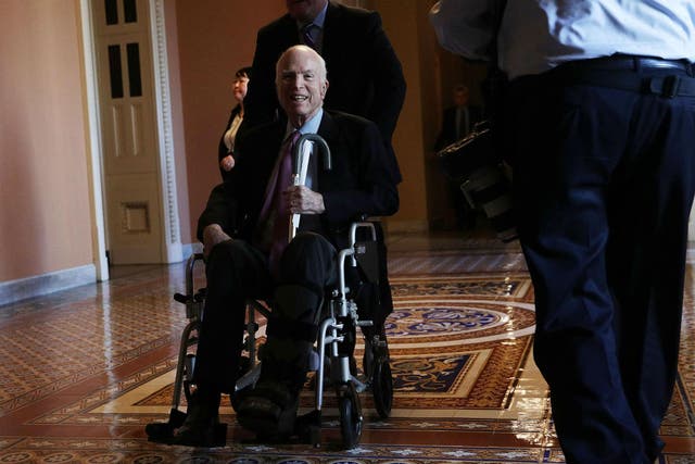 Senator John McCain passes by on a wheelchair in a hallway at the Capitol December 1, 2017 in Washington, DC