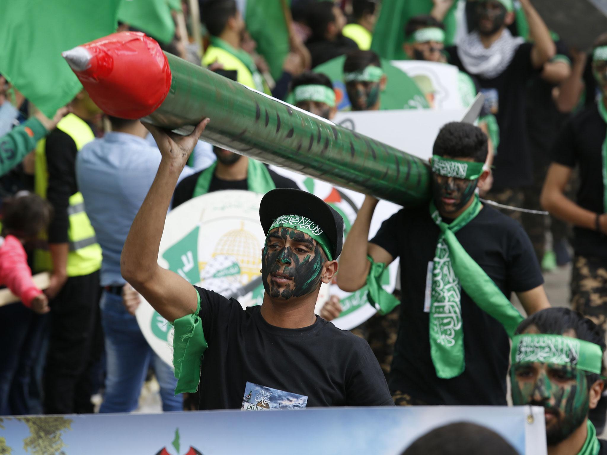 Palestinian Hamas supporters carry a model of a missile during a rally marking the 30th anniversary of Hamas movement, in the West Bank City of Nablus