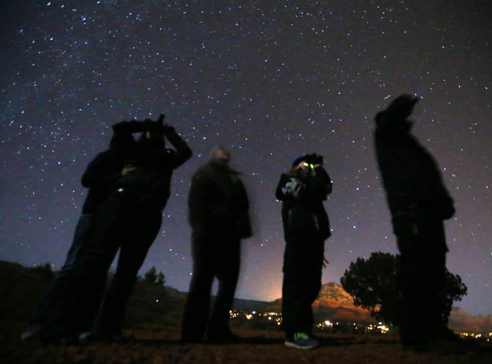 People use night vision goggles to look at the night sky during a UFO tour in the desert outside Sedona, Arizona
