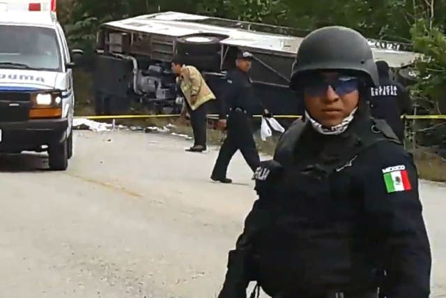 Mexican police officers standing guard in the area where a bus driving tourists to Chacchoben archaeological site overturned