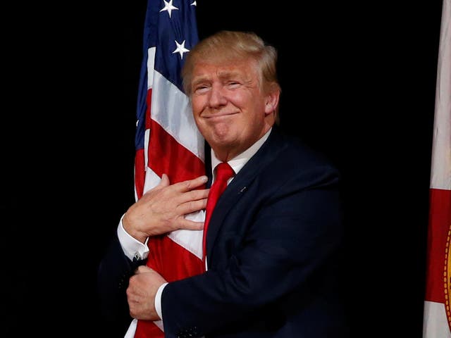 Donald Trump hugs a US flag at a rally with supporters in Tampa, Florida, in 2016