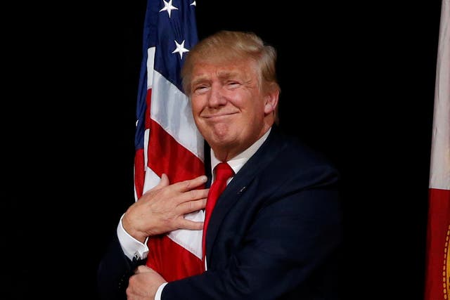 Donald Trump hugs a US flag at a rally with supporters in Tampa, Florida, in 2016