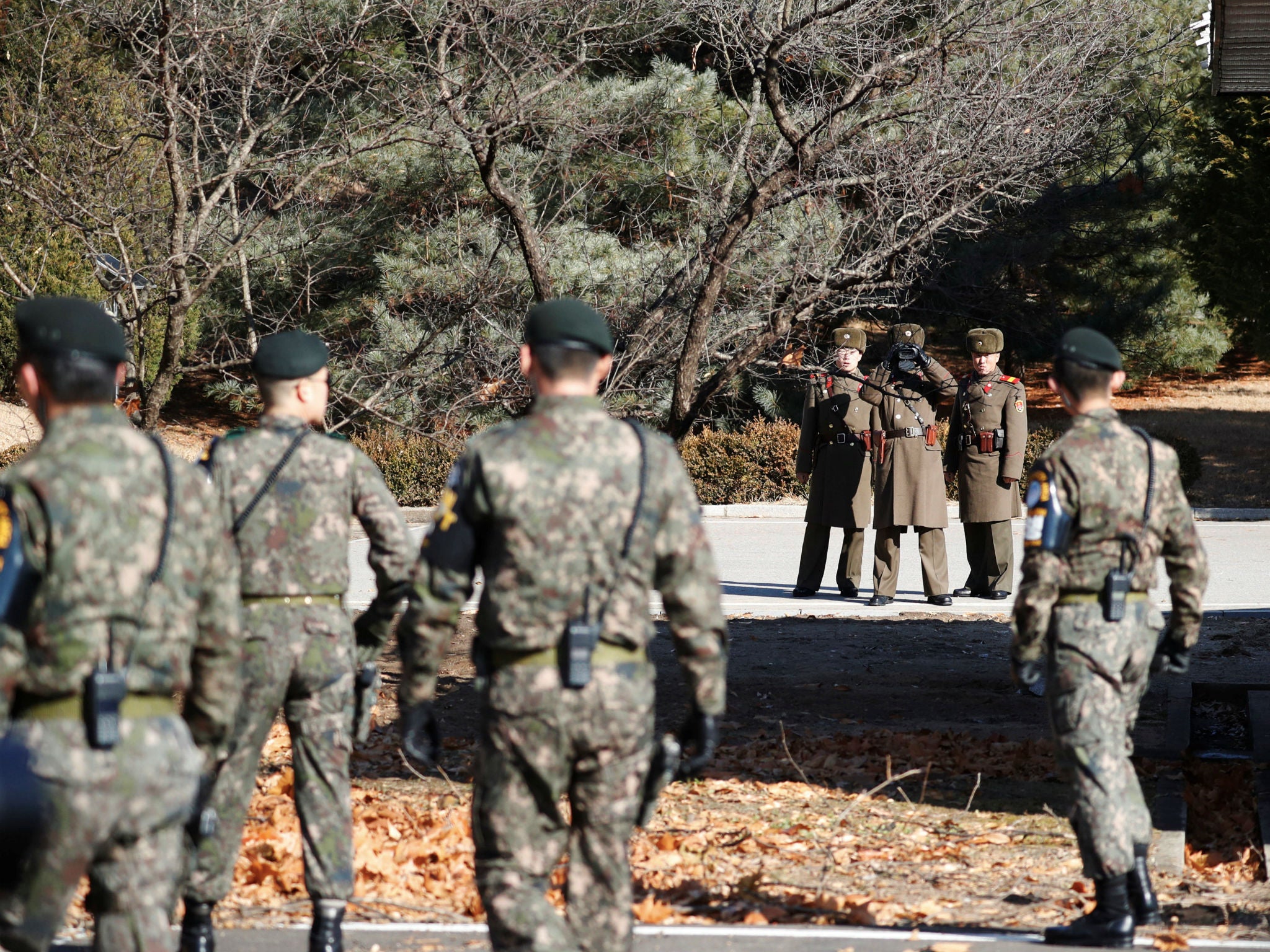 South and North Korean soldiers keep watch each other next to a spot where a North Korean has defected crossing the border on November 13, at the truce village of Panmunjom inside the demilitarized zone, South Korea