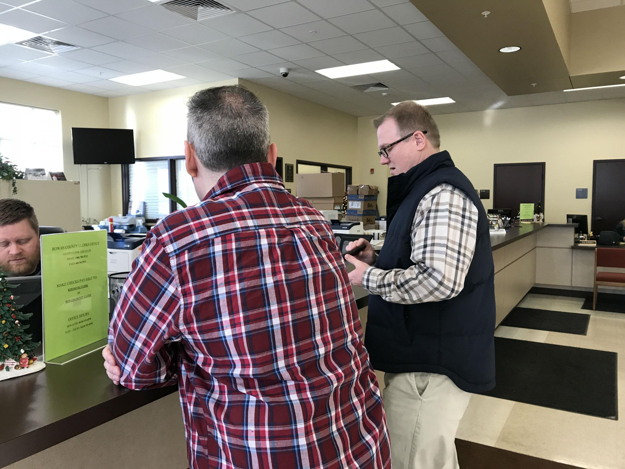 David Ermold (right) collects a new car registration at the counter of the county clerk’s office