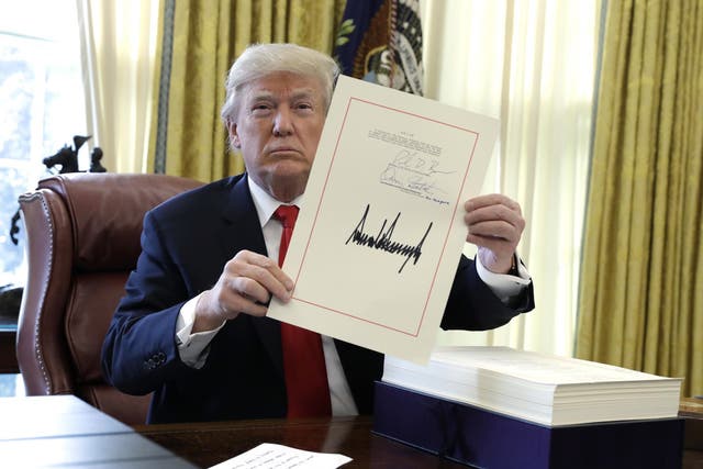 President Donald Trump displays the $1.5 trillion tax overhaul package he had just signed
