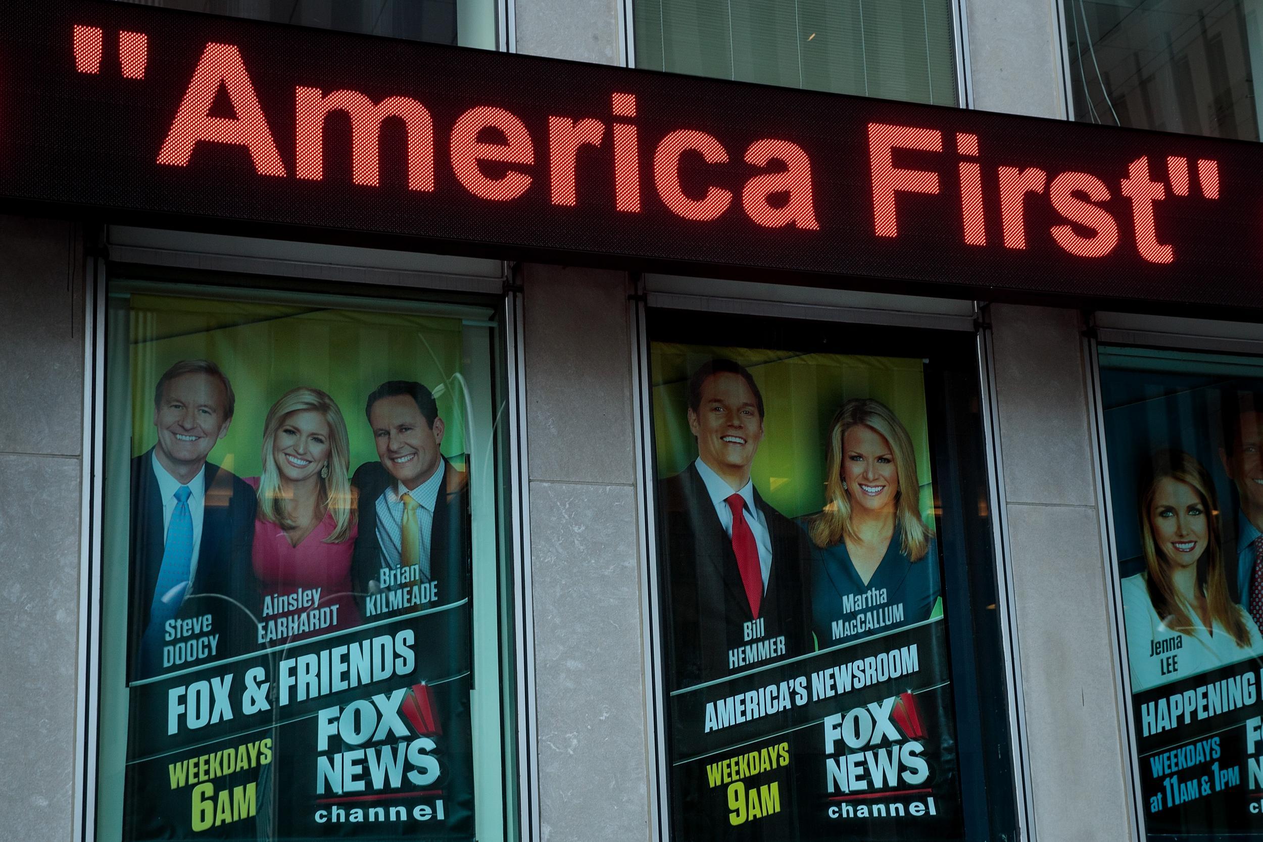 At left, an advertisement for 'Fox And Friends' programme is displayed outside of the Fox News studio in New York City.