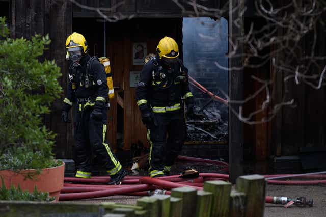 Firefighters move equipment and survey the damage after a fire destroyed buildings at London Zoo