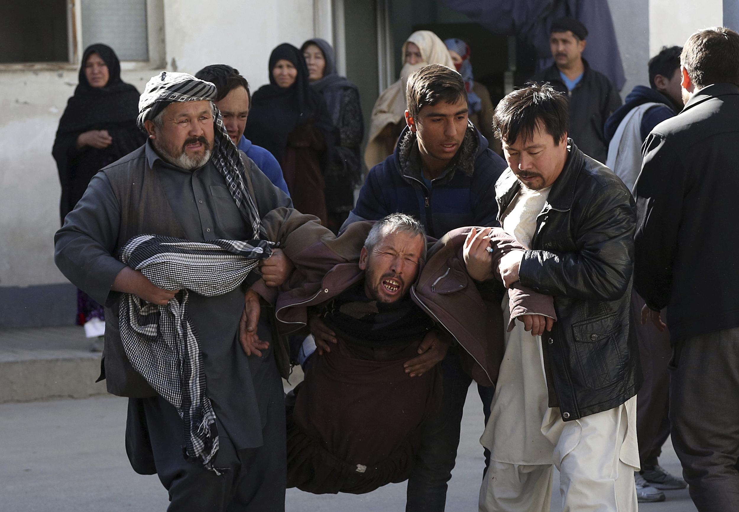 A distraught man is carried following the suicide attack in Kabul, Afghanistan