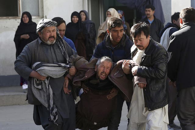 A distraught man is carried following the suicide attack in Kabul, Afghanistan